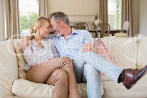 Romantic couple sitting on sofa with arm around in living room