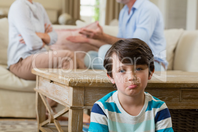 Sad boy listening to his parents arguing