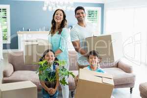 Parents and kids holding cardboard boxes in living room at home