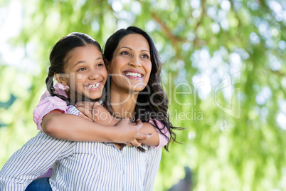 Happy mother giving piggyback ride to her daughter