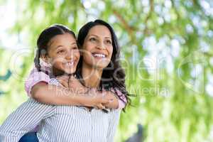 Happy mother giving piggyback ride to her daughter