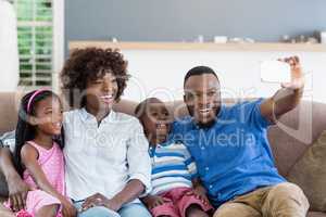 Happy family taking a selfie from mobile phone in living room