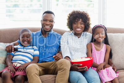 Family and kids watching television while having popcorn in living room