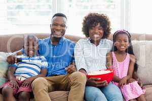 Family and kids watching television while having popcorn in living room