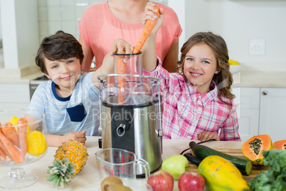 Mother and his two kids making fresh fruit juice in kitchen