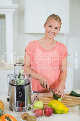 Smiling woman cutting a cucumber on chopping board