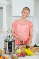 Smiling woman cutting a cucumber on chopping board