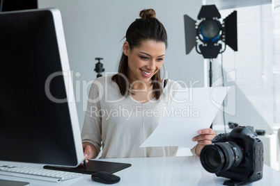 Female photographer using graphic tablet at desk