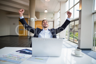 Businessman sitting at desk with arms outstretched