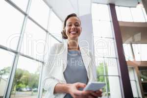 Cheerful businesswoman holding mobile phone