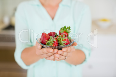Beautiful woman holding glass of strawberry in kitchen