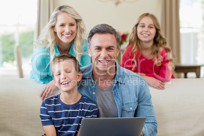 Portrait of smiling parents and kids with laptop in living room