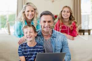 Portrait of smiling parents and kids with laptop in living room