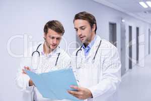 Doctors having discussion on file in corridor