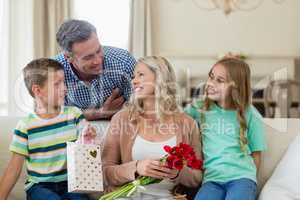 Parents and kids interacting on sofa with present in living room