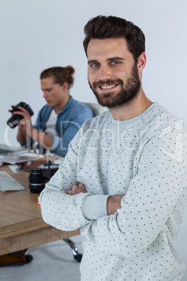 Smiling photographer standing with his arms crossed in studio