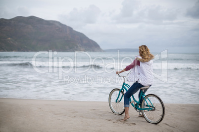 Mature woman riding bicycle on the beach