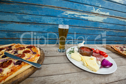 Italian pizza served with glass of beer on wooden plank