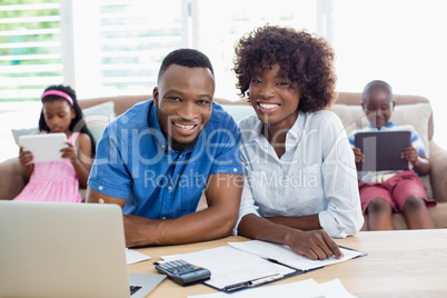 Portrait of couple sitting with bills and calculator on table
