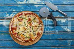 Delicious pizza served on pizza tray with cutter and knife on wooden plank