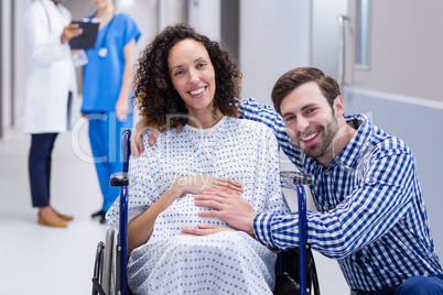 Portrait of man touching pregnant woman belly in corridor