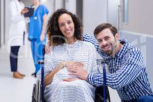 Portrait of man touching pregnant woman belly in corridor