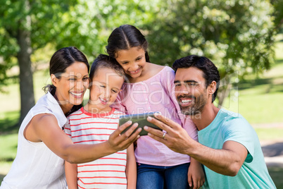 Happy family taking selfie from mobile phone in park