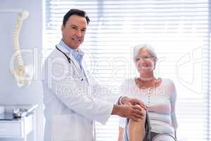 Portrait of physiotherapist giving knee therapy to senior woman