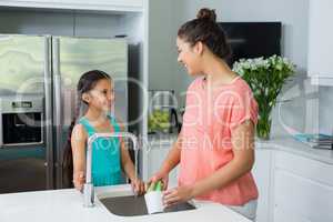 Mother assisting her daughter in cleaning vessel