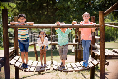 Kids standing and smiling on a playground ride in park