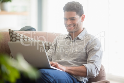 Man sitting on sofa and using laptop in living room