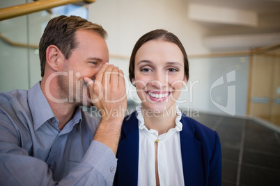 Businessman whispering something to his colleague