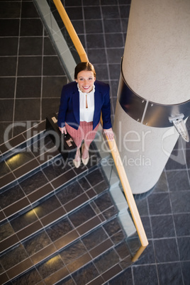 Businesswoman carrying briefcase standing on staircase