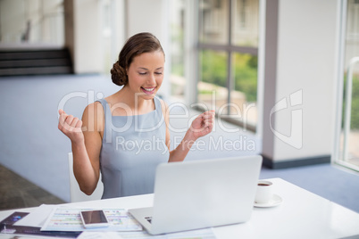 Happy businesswoman using laptop at desk