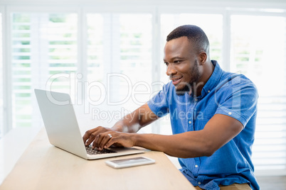 Man sitting at desk and using laptop in living room