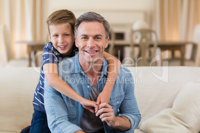 Smiling son embracing a father in living room Smiling son embracing a father in living room