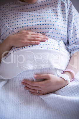 Mid section pregnant woman relaxing on hospital bed