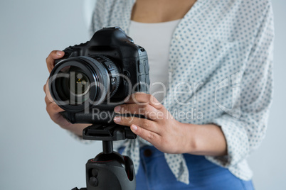 Mid section of female photographer adjusting digital camera