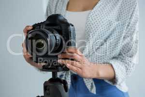Mid section of female photographer adjusting digital camera
