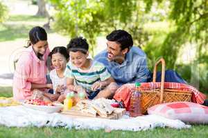 Happy family having breakfast in park