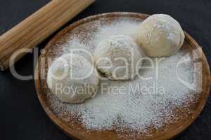 Rolling pin with pizza dough and flour on rolling board