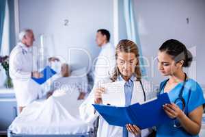 Two female doctors checking the medical report of a patient