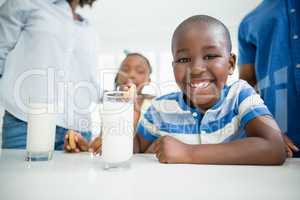 Smiling boy having cookies with milk at home