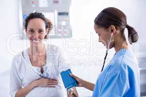 Doctor checking blood pressure of pregnant woman