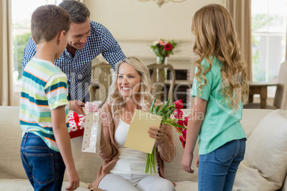 Mother receiving a gift from his kids and husband in living room