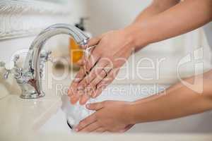 Mother and daughter washing hands in bathroom sink