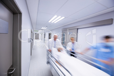 Doctors and nurse pushing emergency stretcher bed in corridor