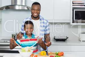 Father and son preparing salad in kitchen at home