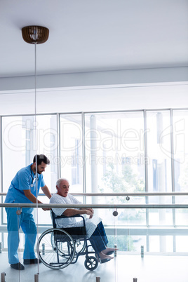 Doctor interacting with male senior patient in passageway