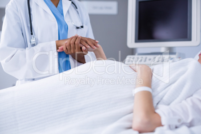 Mid section of doctor comforting pregant woman during ultrasound scan